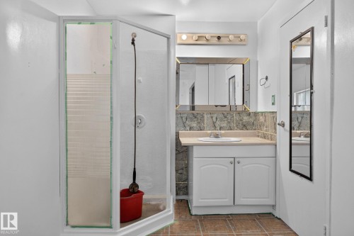 Corner shower enclosure, single vanity with integrated sink, stone-finish backsplash, and neutral floor tiling - 351 Smith Crescent, Rural Parkland County, AB - Indoor Photo Showing Bathroom