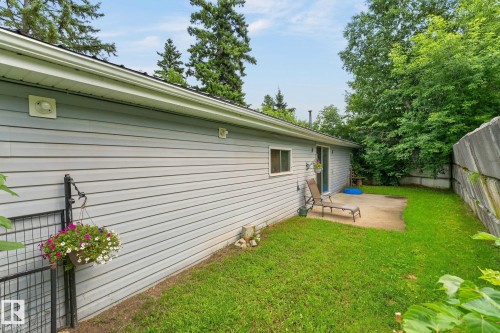 Expansive green space featuring a concrete patio, wood fence, and mature trees - 351 Smith Crescent, Rural Parkland County, AB - Outdoor With Exterior