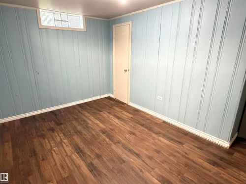 Wood-finish flooring with light blue vertical paneling and white trim - 10416 100 Avenue, Westlock, AB - Indoor Photo Showing Other Room