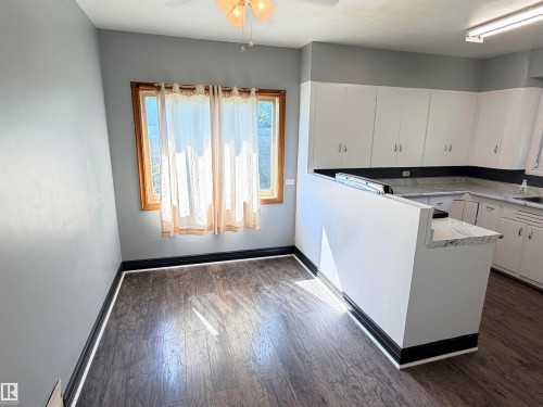Wood-finish flooring, white cabinetry, light-colored countertops, and ceiling fan - 10416 100 Avenue, Westlock, AB - Indoor Photo Showing Other Room