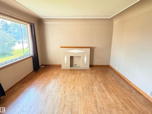 Wood-finish flooring, built-in decorative fireplace, large picture window, and neutral wall tones - 10416 100 Avenue, Westlock, AB - Indoor Photo Showing Other Room