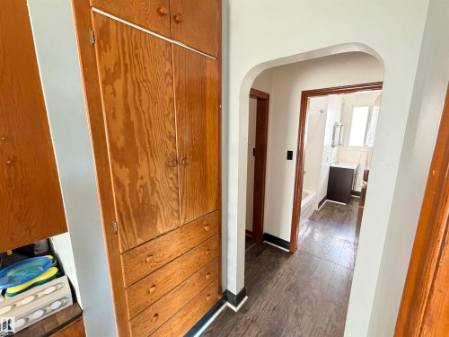 Integrated wood-finish cabinetry with drawers, arched hallway entrance, and wood-finish flooring - 10416 100 Avenue, Westlock, AB - Indoor Photo Showing Other Room