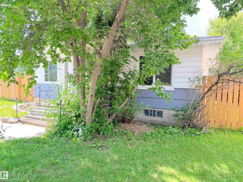 Siding exterior with a decorative wrought iron handrail, wood plank stairs, and a partial wood fence - 10416 100 Avenue, Westlock, AB - Outdoor