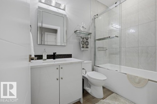 White vanity with integrated sink, black faucet, and mirrored backsplash - 3303 Soleil Boulevard, Beaumont, AB - Indoor Photo Showing Bathroom