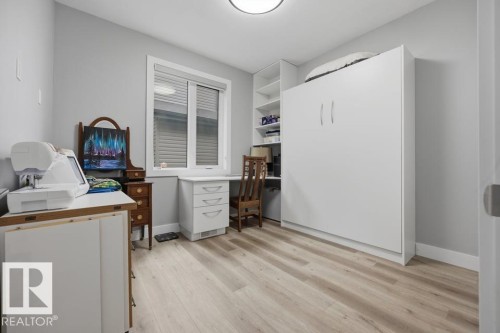 Light wood-finish flooring with a built-in Murphy bed, integrated shelving, and a desk with storage drawers - 3303 Soleil Boulevard, Beaumont, AB - Indoor