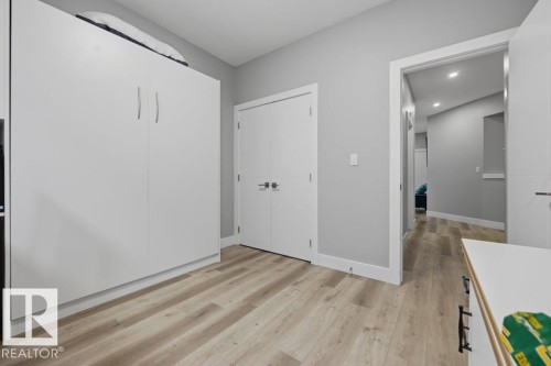 Wood-finish flooring with light gray walls, built-in storage cabinetry, and white interior doors - 3303 Soleil Boulevard, Beaumont, AB - Indoor Photo Showing Other Room