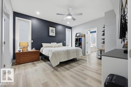 Recessed ceiling lighting, a modern ceiling fan, wood-finish flooring, and a doorway leading to a bathroom with a built-in tub - 3303 Soleil Boulevard, Beaumont, AB - Indoor Photo Showing Bedroom
