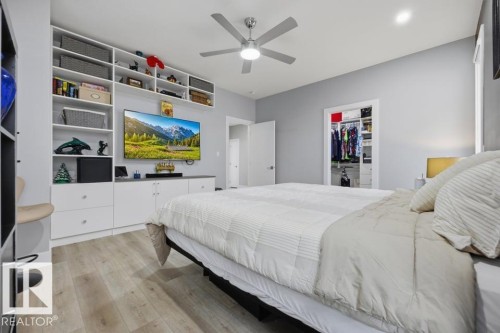 Built-in shelving and cabinetry with ample storage, ceiling fan, wood-finish flooring, and recessed lighting - 3303 Soleil Boulevard, Beaumont, AB - Indoor Photo Showing Bedroom