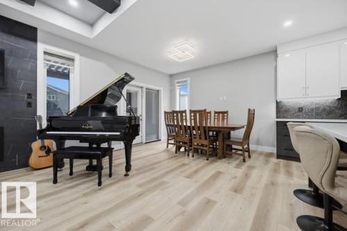 Open-concept space featuring wood-finish flooring, a contemporary fireplace with dark tile surround, and sliding glass doors - 3303 Soleil Boulevard, Beaumont, AB - Indoor Photo Showing Dining Room