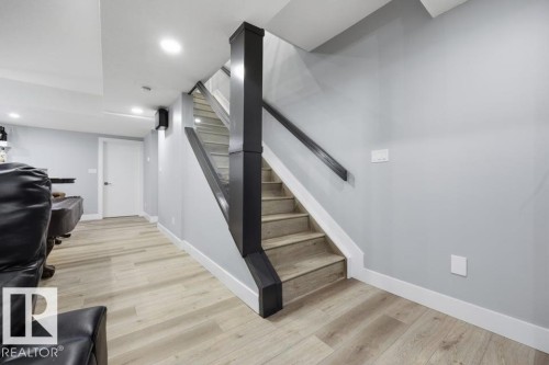 Wood-finish flooring, recessed lighting, and a contemporary staircase with dark wood newel posts and handrails - 3303 Soleil Boulevard, Beaumont, AB - Indoor Photo Showing Other Room