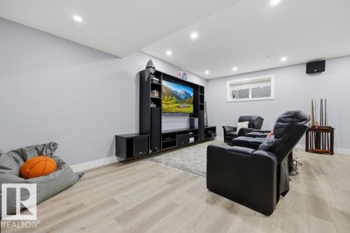 Recessed ceiling lighting, light-toned wood-finish flooring, a built-in media center, and light gray wall paint - 3303 Soleil Boulevard, Beaumont, AB - Indoor