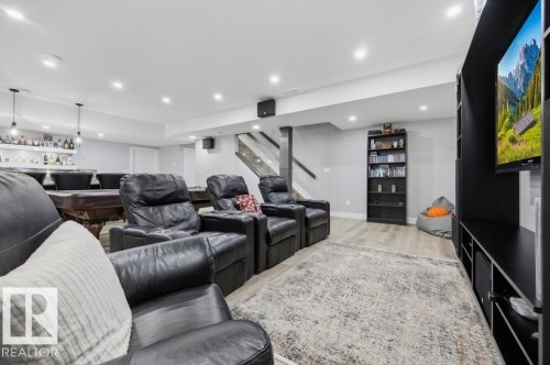 Recessed lighting illuminates the space, featuring wood-finish flooring, a built-in wet bar with pendant lighting, and a pool table - 3303 Soleil Boulevard, Beaumont, AB - Indoor