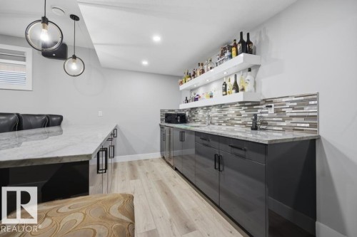 Wet bar featuring a rectangular sink, multi-tone mosaic tile backsplash, and floating shelves - 3303 Soleil Boulevard, Beaumont, AB - Indoor