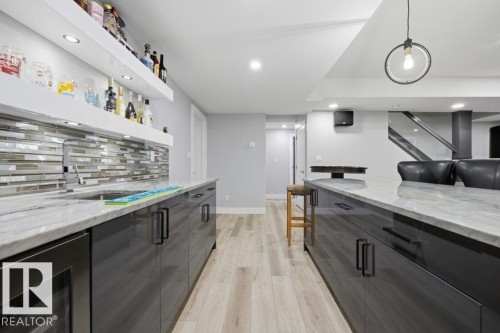 Kitchenette featuring a stainless steel sink, tile backsplash, and light wood-finish flooring - 3303 Soleil Boulevard, Beaumont, AB - Indoor Photo Showing Kitchen