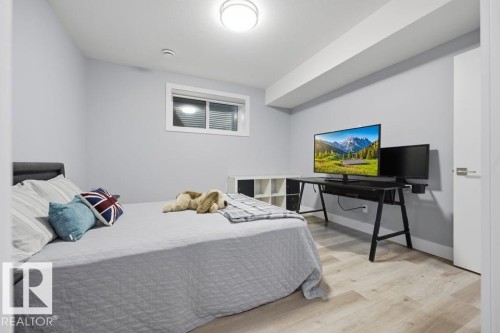 Recessed window with white trim, light-toned wood-finish flooring, light gray walls, and a flush-mounted ceiling light fixture - 3303 Soleil Boulevard, Beaumont, AB - Indoor Photo Showing Bedroom