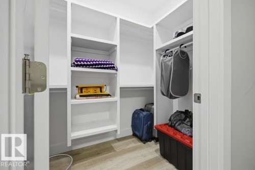 Built-in white shelving, integrated hanging rod, light wood-finish flooring, and white walls - 3303 Soleil Boulevard, Beaumont, AB - Indoor
