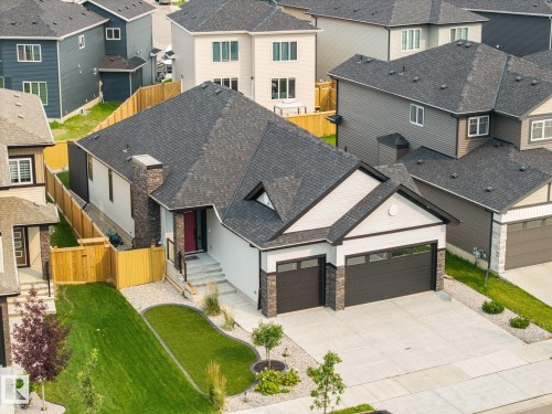 Contemporary home featuring a dual-car garage, stone and siding exterior, concrete driveway, and a manicured lawn - 3303 Soleil Boulevard, Beaumont, AB - Outdoor