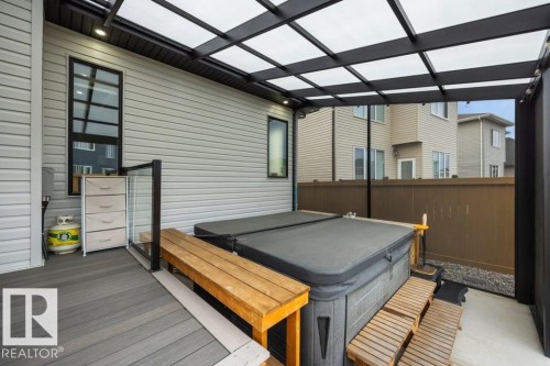 Outdoor hot tub with wooden steps, covered by a black framed patio roof with translucent panels, and complemented by a wooden deck surface - 3303 Soleil Boulevard, Beaumont, AB - Outdoor With Deck Patio Veranda With Exterior