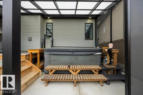 Covered patio featuring a hot tub with cover, wood-finish steps, and a translucent panel roof - 3303 Soleil Boulevard, Beaumont, AB - Outdoor With Exterior