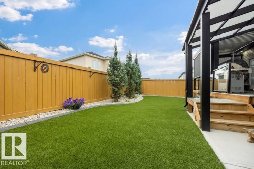 Expansive artificial turf lawn bordered by a wood privacy fence and a white gravel planter bed - 3303 Soleil Boulevard, Beaumont, AB - Outdoor
