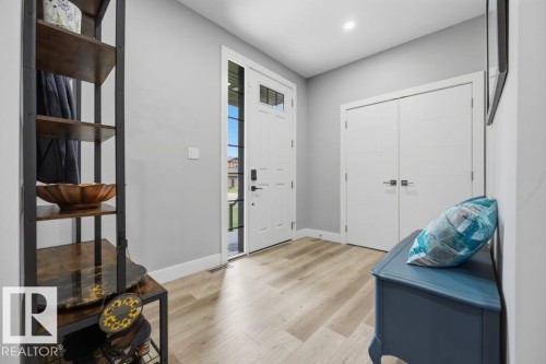 Light wood-finish flooring, white entry door with frosted glass panel, recessed lighting, and white bi-fold doors - 3303 Soleil Boulevard, Beaumont, AB - Indoor Photo Showing Other Room