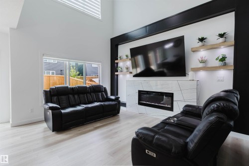 White walls with light wood-finish flooring - 5320 Kimball Place Sw, Edmonton, AB - Indoor Photo Showing Living Room With Fireplace