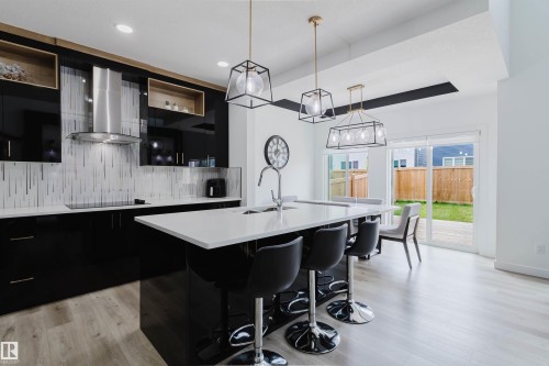Kitchen featuring gloss black cabinetry, white countertops, tile backsplash, and stainless steel range hood - 5320 Kimball Place Sw, Edmonton, AB - Indoor Photo Showing Kitchen With Upgraded Kitchen