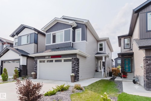 Contemporary exterior featuring multi-toned siding, stone accents, an attached garage, a paved driveway, and a covered entry - 5320 Kimball Place Sw, Edmonton, AB - Outdoor With Facade