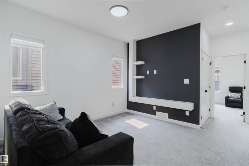 Recessed lighting, light-colored carpeting, multiple windows, a modern accent wall with shelving, and a flat ceiling light fixture - 5320 Kimball Place Sw, Edmonton, AB - Indoor
