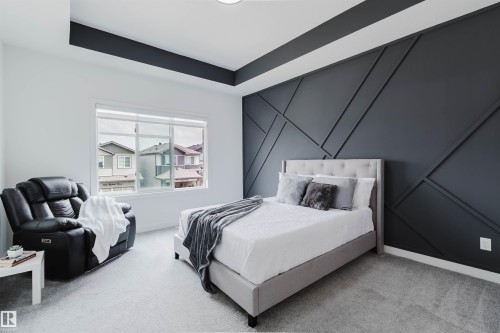 Accent wall with geometric trim, recessed ceiling detail, ceiling-mounted lighting, large window, and light-toned carpeting - 5320 Kimball Place Sw, Edmonton, AB - Indoor Photo Showing Bedroom