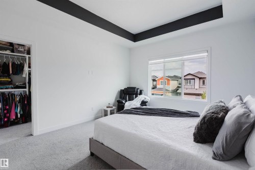 Recessed ceiling with contrasting accent, expansive window, built-in closet with shelving, and light-toned carpeting - 5320 Kimball Place Sw, Edmonton, AB - Indoor Photo Showing Bedroom
