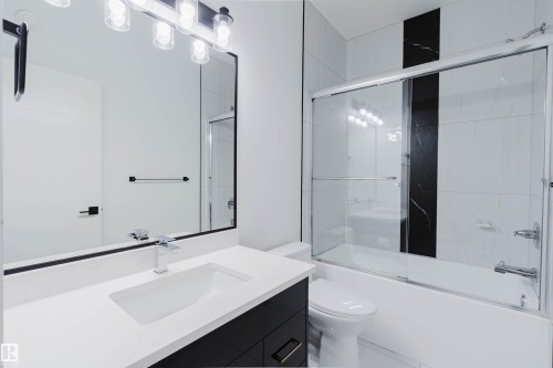 Modern bathroom featuring a vanity with an integrated rectangular sink, a wall-mounted light fixture, and a framed mirror - 5320 Kimball Place Sw, Edmonton, AB - Indoor Photo Showing Bathroom