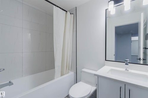 Bright bathroom featuring a bathtub with subway tile surround, white vanity with an undermount sink, and a framed mirror - 5320 Kimball Place Sw, Edmonton, AB - Indoor Photo Showing Bathroom