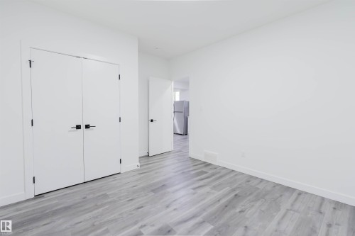 Wood-finish flooring with white walls - 5320 Kimball Place Sw, Edmonton, AB - Indoor Photo Showing Other Room