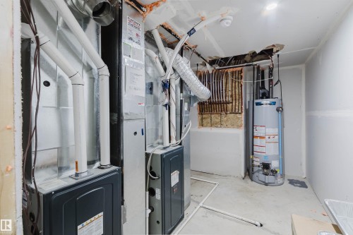 Utility room featuring furnace units, water heater, and exposed insulation - 5320 Kimball Place Sw, Edmonton, AB - Indoor Photo Showing Basement