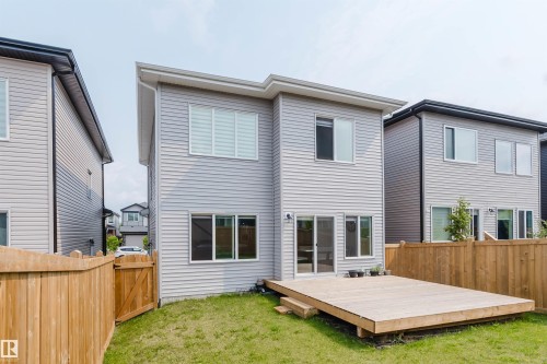 Two-story exterior with light gray siding, multiple windows, and a ground-level wood deck - 5320 Kimball Place Sw, Edmonton, AB - Outdoor With Exterior