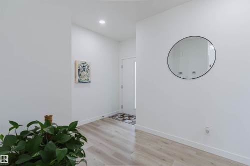 Recessed lighting, wood-finish flooring, white walls, and a white door with a vertical light insert - 5320 Kimball Place Sw, Edmonton, AB - Indoor Photo Showing Other Room
