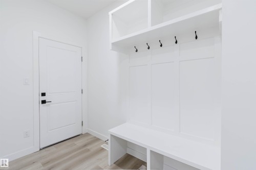 Built-in white storage unit featuring bench seating, upper shelving, and integrated coat hooks - 5320 Kimball Place Sw, Edmonton, AB - Indoor Photo Showing Other Room