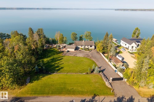 Expansive property featuring a manicured lawn, established landscaping, and a paved driveway with stone pillars - 139 Silver Beach Road, Rural Wetaskiwin County, AB - Outdoor With Body Of Water With View