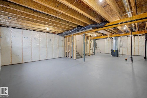 Expansive unfinished lower level featuring exposed wood joists and structural beams, insulated exterior walls, and a concrete floor - 5435 Hawthorn Run Sw, Edmonton, AB - Indoor Photo Showing Basement