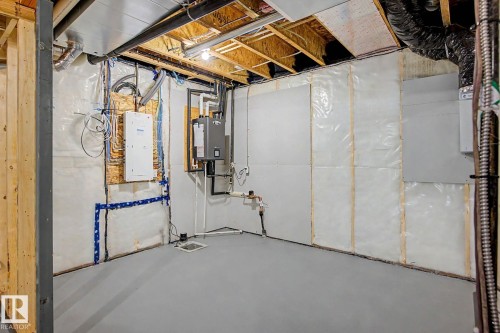 Unfinished basement space featuring exposed wooden joists, utility installations, and a painted concrete floor - 5435 Hawthorn Run Sw, Edmonton, AB - Indoor Photo Showing Basement