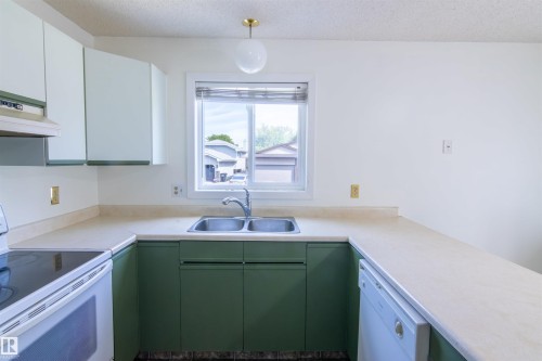 Kitchen featuring a double basin stainless steel sink, a window above the sink, a white electric range, a white dishwasher, and overhead globe lighting - 4903 11A Avenue Nw, Edmonton, AB - Indoor Photo Showing Kitchen With Double Sink
