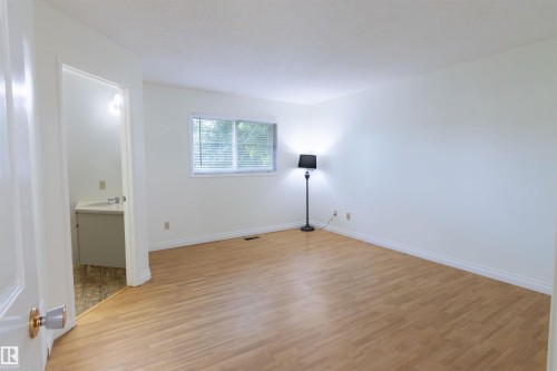 Spacious room featuring wood-finish flooring and a window with blinds - 4903 11A Avenue Nw, Edmonton, AB - Indoor Photo Showing Other Room