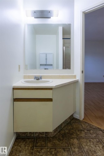 Bathroom vanity featuring a single basin sink, white countertop, and integrated storage cabinetry - 4903 11A Avenue Nw, Edmonton, AB - Indoor Photo Showing Bathroom
