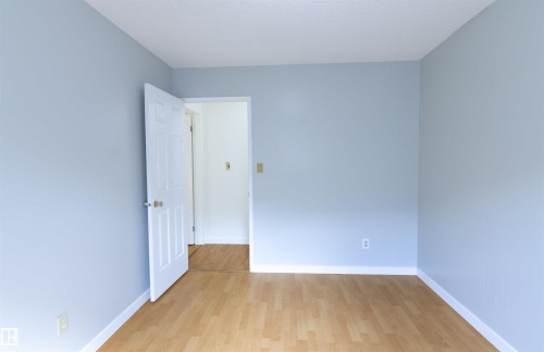Interior room featuring light blue walls and wood-finish flooring - 4903 11A Avenue Nw, Edmonton, AB - Indoor Photo Showing Other Room