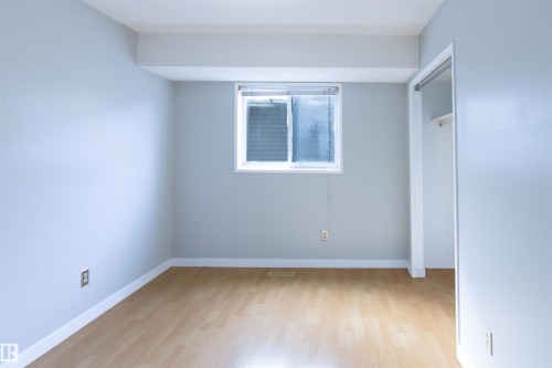 Spacious room featuring light wood-finish flooring, light gray walls, a window with horizontal blinds, and a built-in closet with an open doorway - 4903 11A Avenue Nw, Edmonton, AB - Indoor Photo Showing Other Room