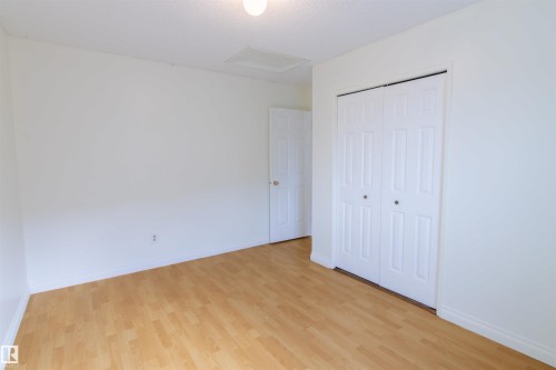 Spacious bedroom showcasing pristine white walls, wood-finish flooring throughout, and dual closets with white panel doors providing ample storage - 4903 11A Avenue Nw, Edmonton, AB - Indoor Photo Showing Other Room