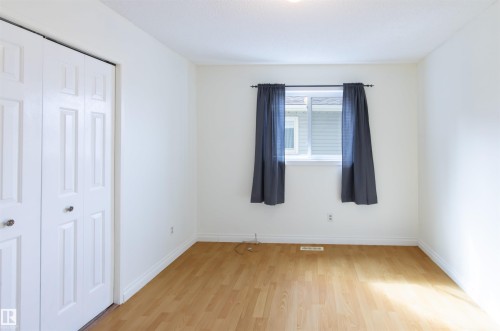 Room featuring wood-finish flooring, white baseboards, and bright white walls - 4903 11A Avenue Nw, Edmonton, AB - Indoor Photo Showing Other Room