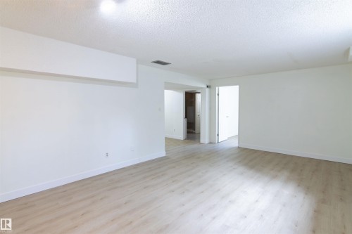 Spacious room featuring light wood-finish flooring, white walls, white baseboards, and a recessed ceiling light - 4903 11A Avenue Nw, Edmonton, AB - Indoor Photo Showing Other Room