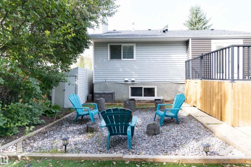 Inviting backyard retreat featuring a gravel-base patio with multiple Adirondack seating, mature landscaping with established trees, wooden privacy fencing, and direct access to the home's lower level - 4903 11A Avenue Nw, Edmonton, AB - Outdoor With Deck Patio Veranda With Exterior